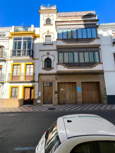 a white car parked in front of a building at La Banda Rooftop Hostel in Seville
