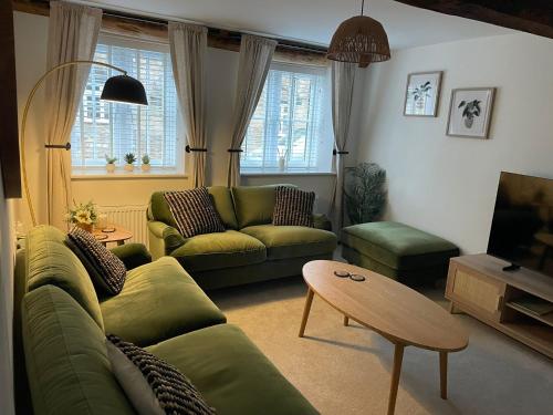 a living room with a green couch and a table at Luxury Lechlade cottage - Character and charm in Lechlade