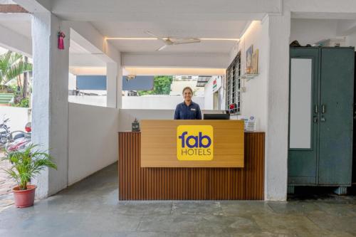 a woman standing behind a reception desk in a building at FabHotel Saraswati Niwas in Pune