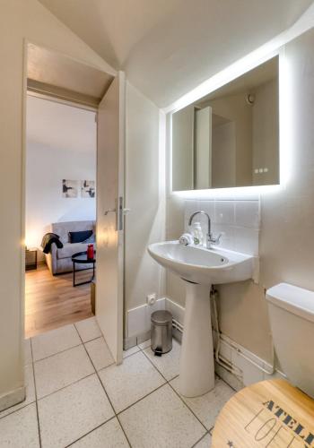 a bathroom with a sink and a toilet and a bedroom at Le Clemenceau 2 in Margny-lès-Compiègne