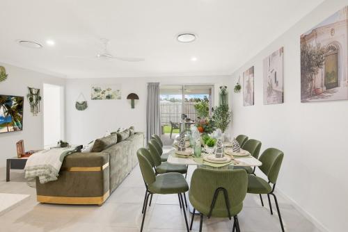 MarsdenLogan Reserv 5BR Near Large Business District Fully Air-Conditioned With Parking的客厅里有一张桌子和几把绿色的椅子