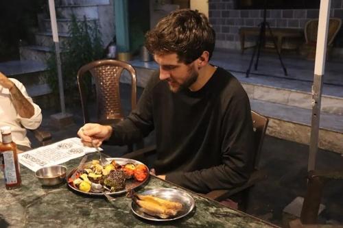 达兰萨拉DharteHouse Villa for Conscious Living and Events的一位男士坐在桌边，面前摆着一盘食物