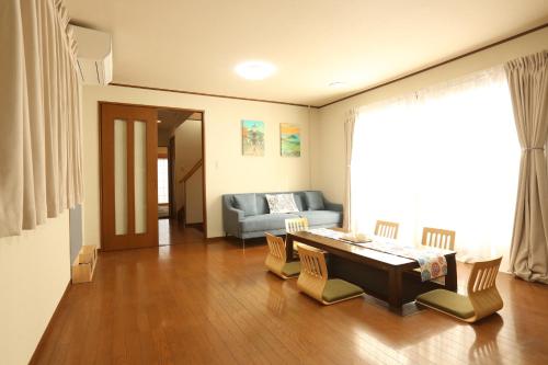 a living room with a table and chairs and a couch at 庭音日和 2つの半露天壺湯でくつろぐ宿 大家族向け広々一棟貸し 駐車場2台 浴室2箇所 in Omihachiman