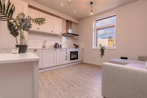 a kitchen with white cabinets and a couch and a window at Cosy serviced flat in Westbury on Trym in Bristol