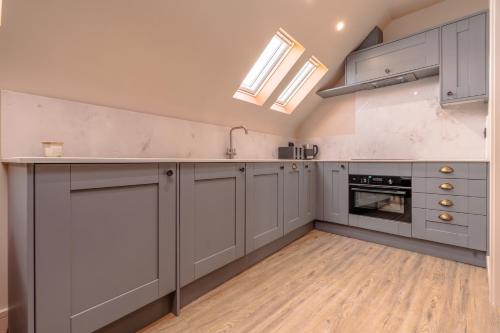 a large kitchen with gray cabinets and a wooden floor at High Street Hideaway, private entrance, parking in Bristol
