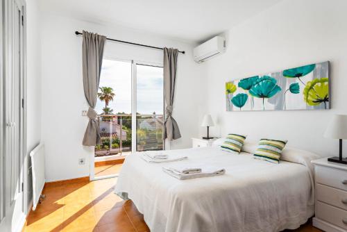 a white bedroom with a bed and a large window at Villa Varadero by Escape Home in Alaior