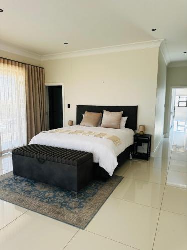 una grande camera da letto con un grande letto con una panca in pelle nera di Duinen Suites a Walvis Bay