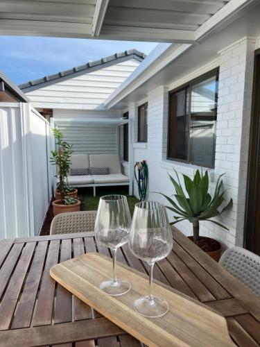 two wine glasses sitting on a wooden table on a patio at Casa Al Mare- family and pet friendly, close to everything in Gold Coast