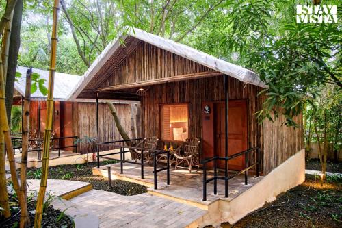una piccola cabina nel bosco con tavolo e sedie di StayVista's Timber Cottage - Cozy Cottages with Indoor Games a Wādhiware