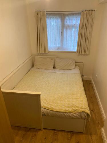 ein kleines Bett in einem Zimmer mit Fenster in der Unterkunft Firs Drive in Cranford