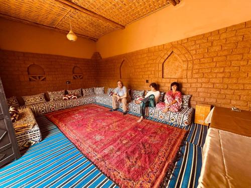 three people sitting on a couch in a living room at Dar Nomads in Mhamid