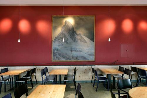 a room filled with tables and chairs with a mural on the wall at 3100 Kulmhotel Gornergrat in Zermatt