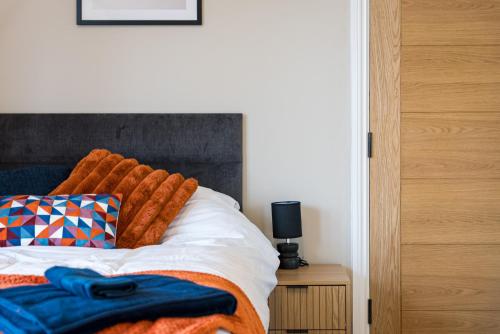 a bed with an orange blanket on top of it at Rosemont ApartHotel in Leeds