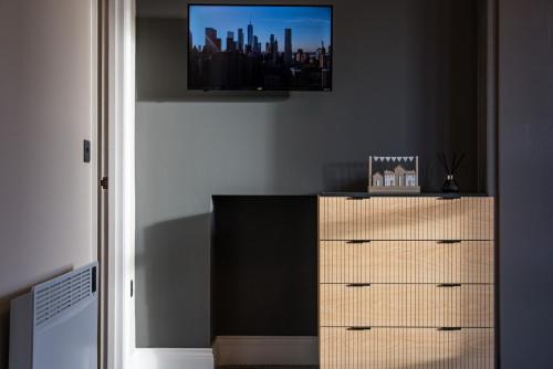 a room with a dresser with a tv on the wall at Rosemont ApartHotel in Leeds