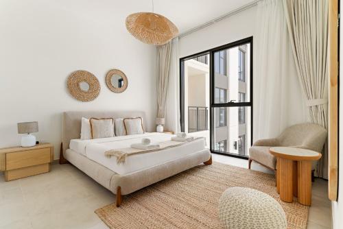 una camera da letto bianca con un letto grande e una sedia di VayK - Chic 2BR in Town Square with Pool View a ‘Ūd al Bayḑāʼ