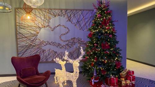 a christmas tree in a living room next to a chair at Hampton By Hilton Venice Isola Nuova in Venice