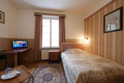 a bedroom with a bed and a desk and a window at Schlosshotel Zamek Zdikov in Zdíkov