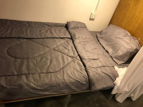 a bed with a gray comforter and two pillows at Reaksa Hostel & Spa - Koh Rong in Kaôh Rŭng (6)