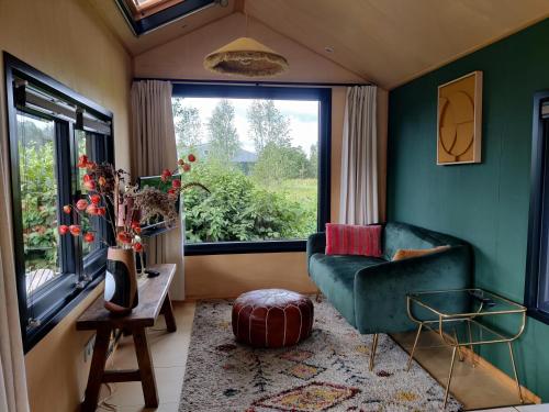 un soggiorno con sedia verde e finestra di Tiny Greenhouse op Boetiekpark de Kas a Scherpenzeel