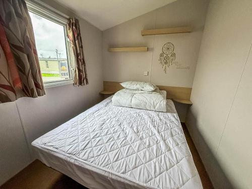 a small bedroom with a bed in a room with a window at Great 8 Berth Caravan For Hire At Seawick Holiday Park In Essex Ref 27227Sw in Clacton-on-Sea