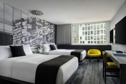 a hotel room with two beds and a yellow chair at The Wade in Chicago