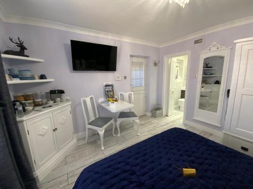 a bedroom with a bed and a table and a tv at THE KNIGHTWOOD OAK a Luxury King Size Bed -En-Suite Space - LYMINGTON NEW FOREST with Private Entrance - Key Box entry-Free Parking & Private Outdoor Seating Area -Full Fibre WiFi -Town ,Shops , Pubs & Solent Way Walking Distance & Complimentary Breakfast in Lymington