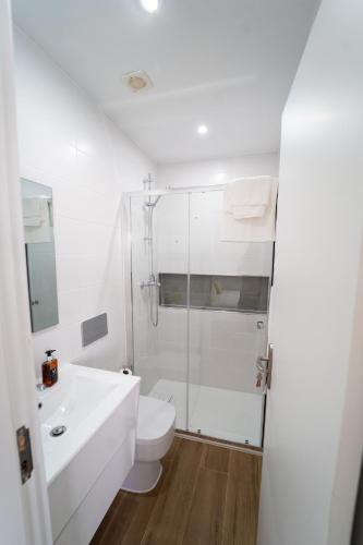 a white bathroom with a toilet and a shower at GREEN STUDIO TARRAFAL - Ap 02 in Tarrafal