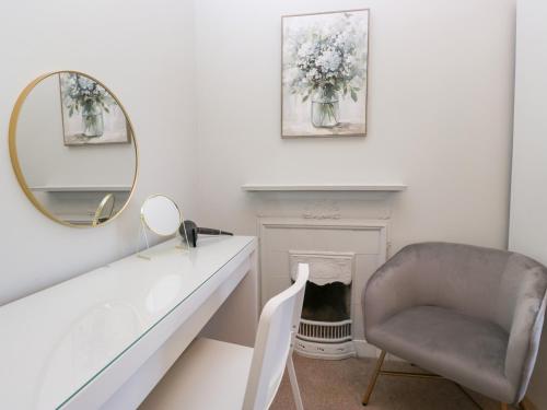 Ein Spiegel und ein Stuhl in einem weißen Raum mit einem Stuhl und einem Kamin in der Unterkunft Rocklands in Shap