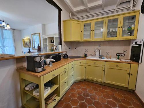 a kitchen with yellow cabinets and a sink at Petit Soleil du matin in Étretat