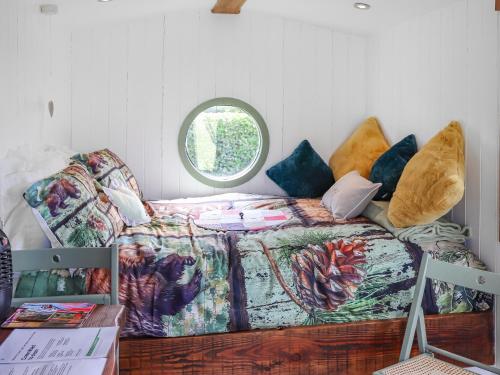 un letto in una camera con divano e finestra di Glan Tywyn Shepherds Hut a Caeʼr-geiliog