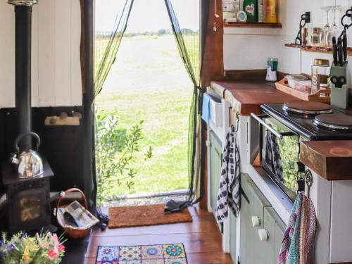 una cucina con finestra affacciata su un campo di Glan Tywyn Shepherds Hut a Caeʼr-geiliog
