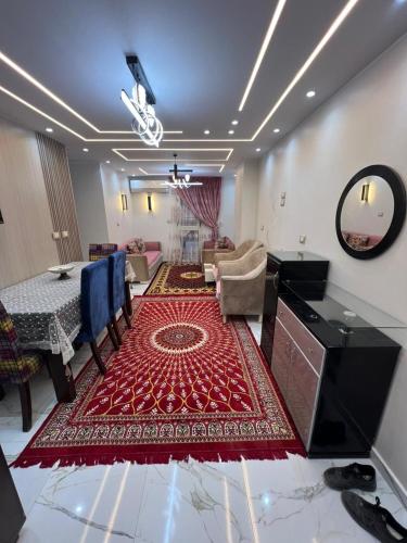a living room with a table and a red rug at Aswan in Nag` el-Ramla