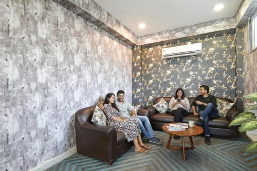 eine Gruppe von Menschen, die in einem Wohnzimmer auf einer Couch sitzen in der Unterkunft Hotel Supreme in Gurgaon