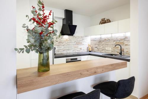 une cuisine avec un vase de fleurs sur un comptoir dans l'établissement Apartma Masada, à Maribor