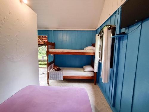 a bedroom with bunk beds in a blue wall at Recanto Ana Valentin in Ilha do Mel