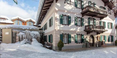 un edificio con finestre con persiane verdi e neve di Villa Egger a Lofer