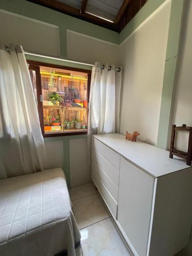 een kleine kamer met een raam en een witte ladekast bij casa celeste in Imbituba