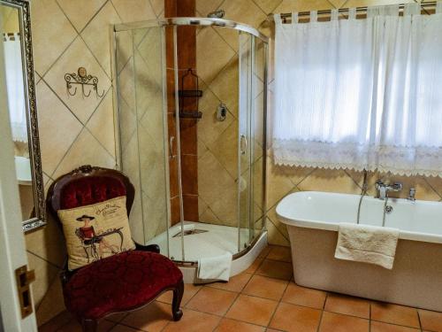 e bagno con vasca e sedia accanto alla doccia. di Mistique Waters Guesthouse a Parys