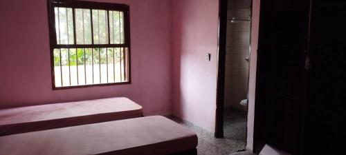 a small room with two beds and a window at Casa Mena Verão in Itanhaém
