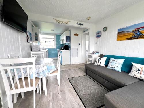 a living room with a couch and a table and a kitchen at Wight Waves Holidays in Sandown