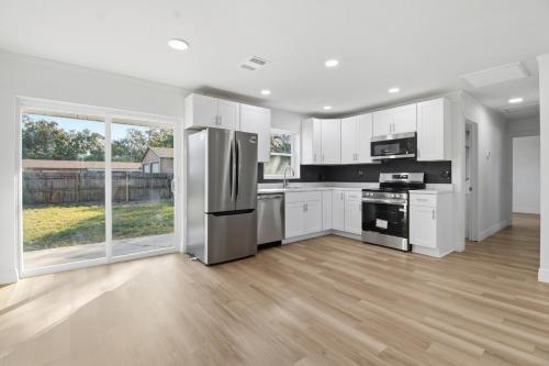 una cucina con armadietti bianchi ed elettrodomestici in acciaio inossidabile di Elegant Auburndale Rooms Near the Speedway & Lake Myrtle ad Auburndale