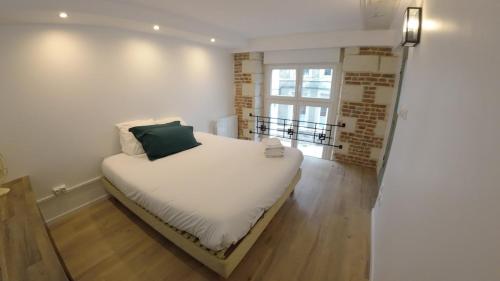 Loft industriel - Cambrai hyper centre ville في كامبراي: سرير أبيض في غرفة بها نافذة