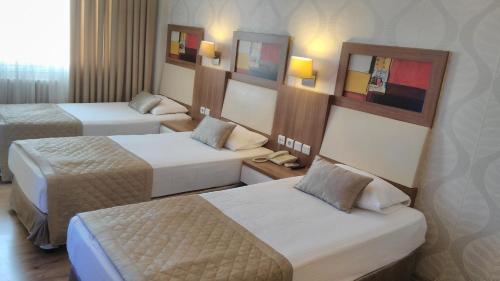 a hotel room with three beds in a room at Hotel Baylan İzmir in Izmir