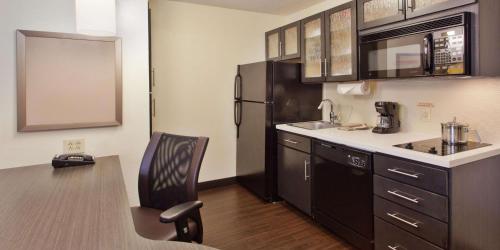 a kitchen with a black refrigerator and a chair at Sonesta Simply Suites Knoxville in Knoxville