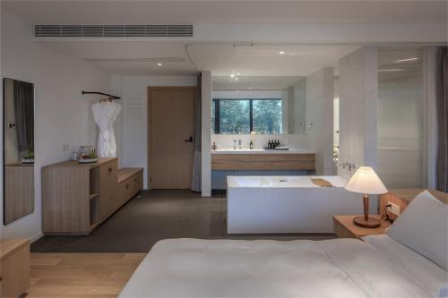 ein Schlafzimmer mit einem weißen Bett und ein Badezimmer in der Unterkunft LOSTVILLA·Green Gable(Anji) in Anji