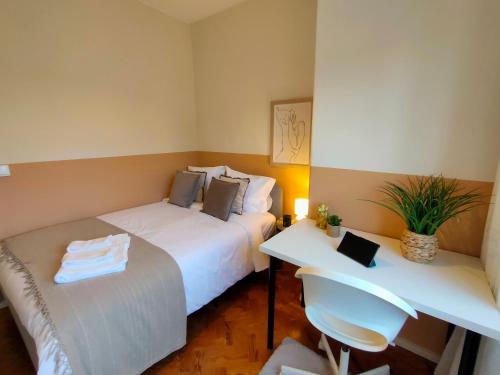 two beds in a small room with a desk and chairs at Lovely room in city centre in Leiria