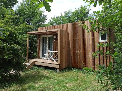 een kleine houten hut met een tafel op een terras bij Studnature in Dunes