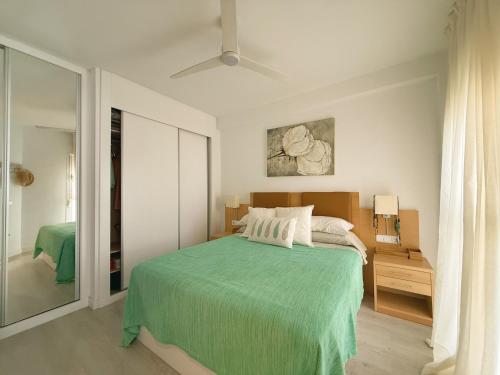 a bedroom with a bed with a green blanket at Ático Dúplex con Jacuzzi en Vera Playa y parking cubierto enorme in Vera