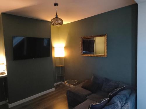 Parkdale-Ideal for Birmingham Airport, International Train Station-Resorts World, BHX, NEC ,JLR & HS2 sites في برمنغهام: غرفة معيشة مع أريكة ومرآة