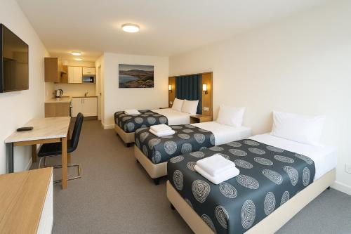 una camera d'albergo con due letti e una scrivania di Eildon Lake Motel a Eildon